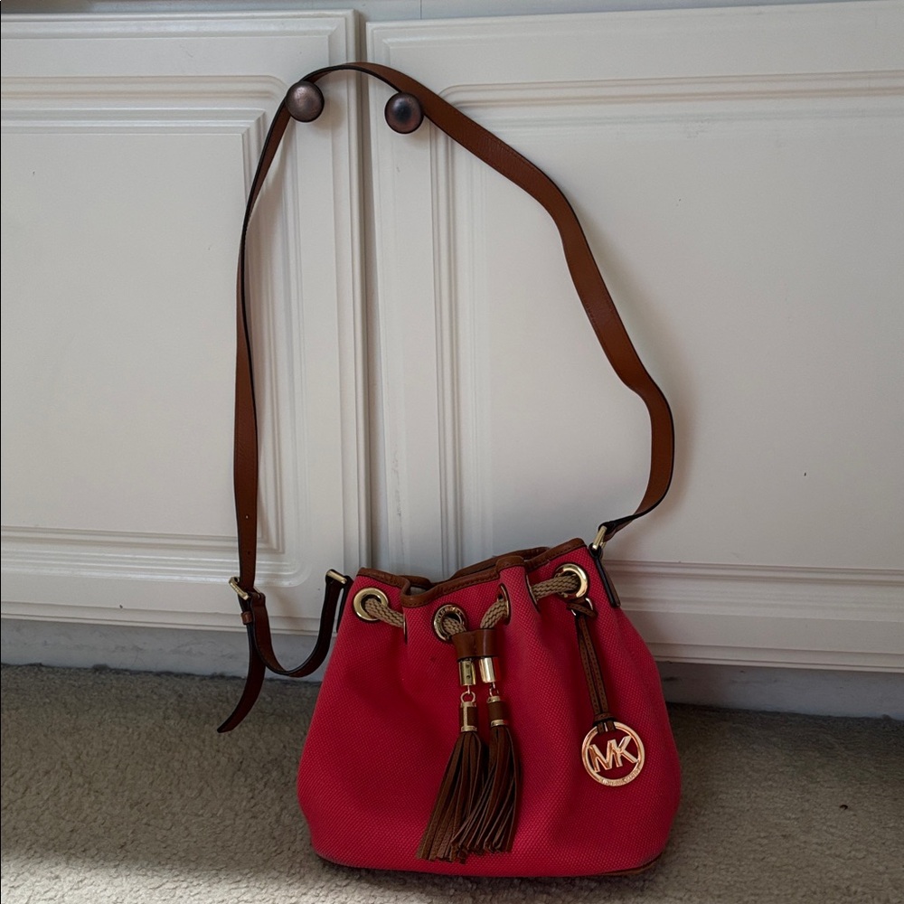 Michael Kors small salmon colored bucket bag with brown leather strap.